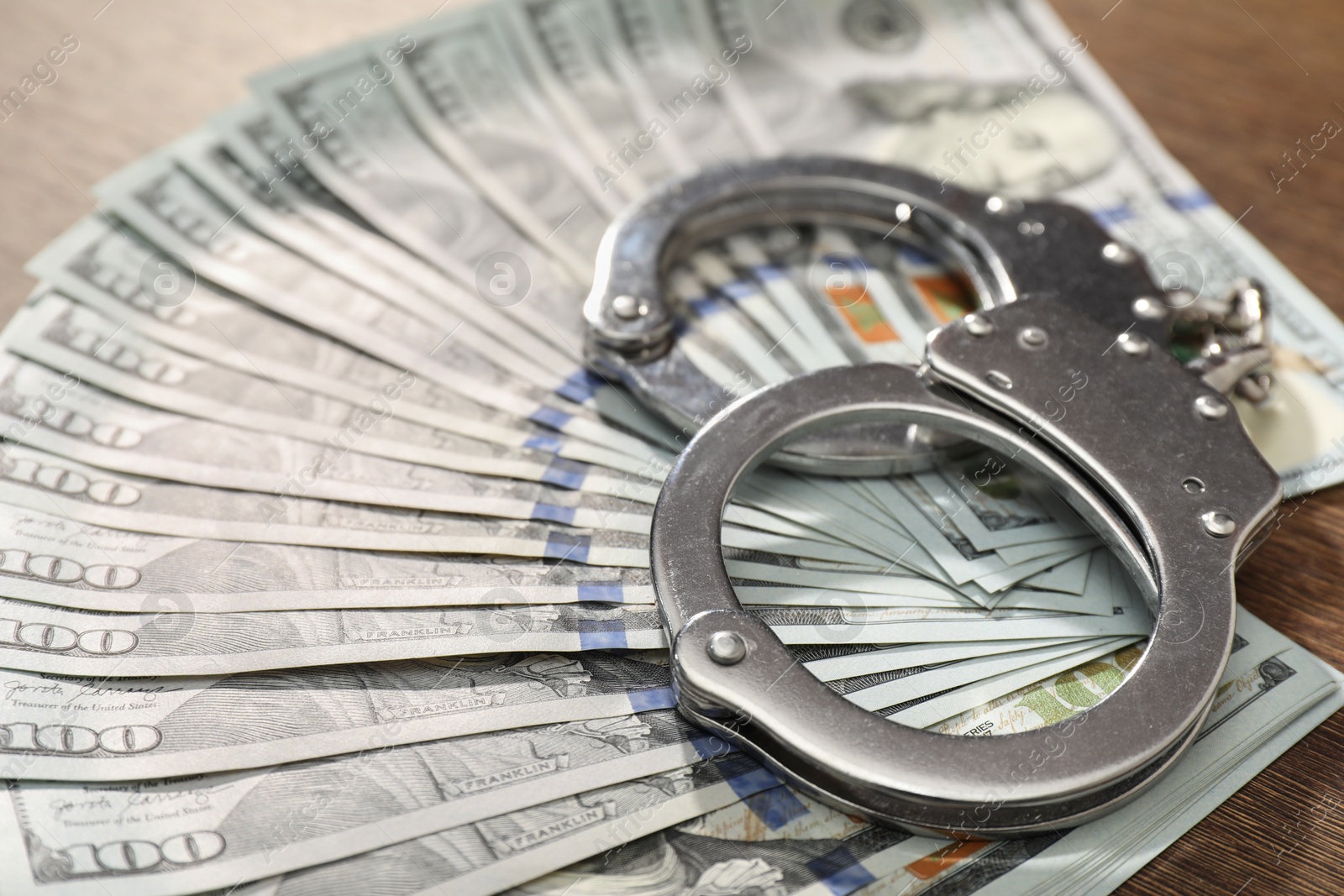 Photo of Handcuffs with dollar banknotes on table, closeup