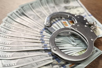 Handcuffs with dollar banknotes on table, closeup