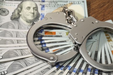 Handcuffs with dollar banknotes on table, closeup