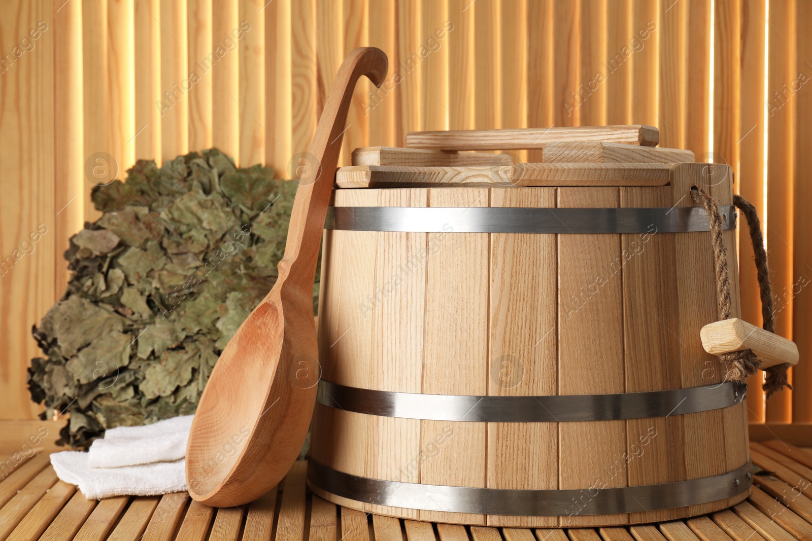 Photo of Sauna equipment. Bucket, oak whisk, towel and ladle on wooden surface