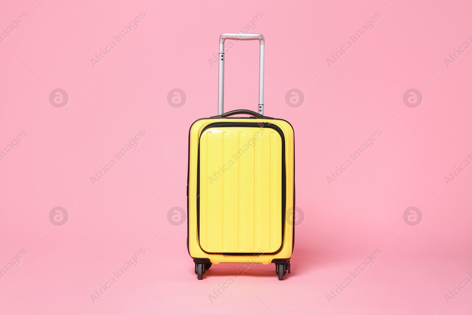 Photo of One new yellow suitcase on pink background