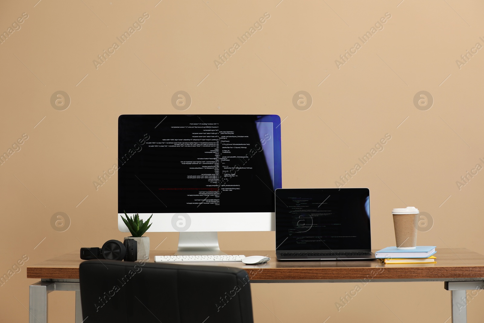 Photo of Programmer's workplace. Modern computer with unfinished code, laptop and other supplies on desk