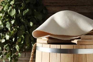 Photo of Sauna equipment. Wooden bucket and felt wool hat indoors, closeup