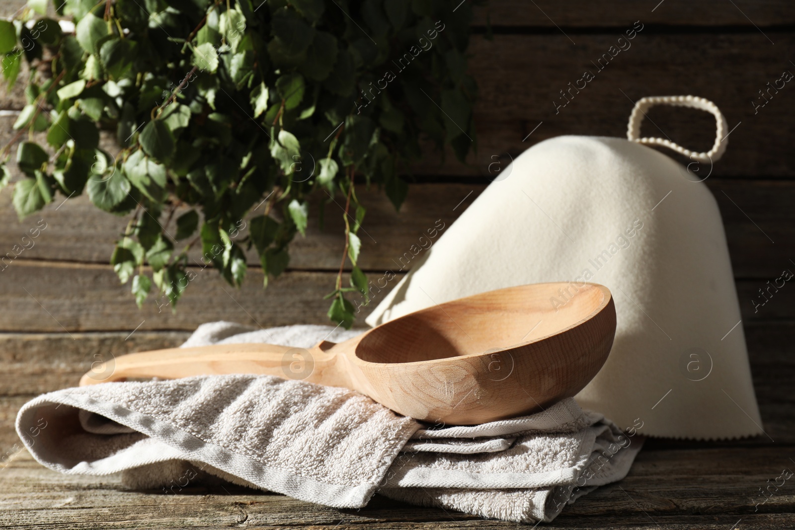 Photo of Sauna equipment. Felt wool hat, ladle and towel on wooden surface