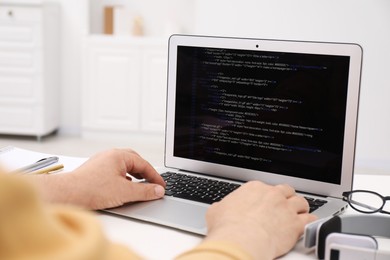 Photo of Programmer working with laptop at white desk in office, closeup