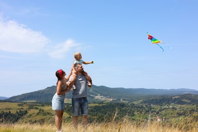 Photo of Happy family flying kite at field under blue sky