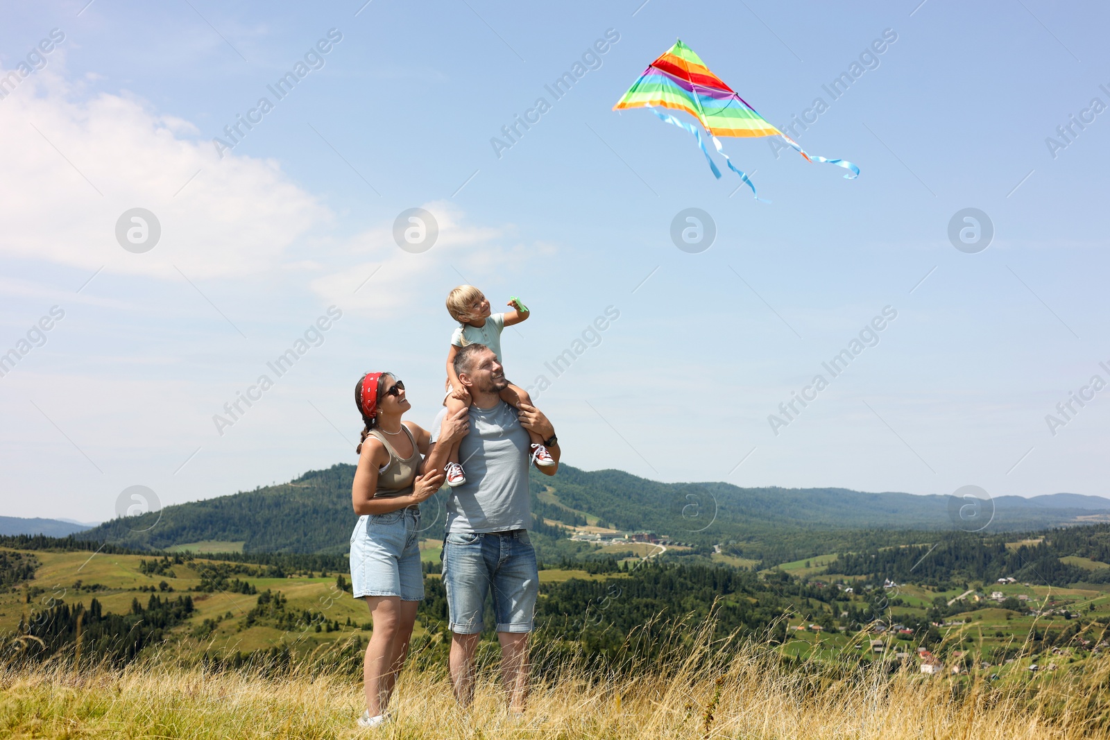 Photo of Happy family flying kite at field under blue sky