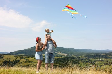 Photo of Happy family flying kite at field under blue sky