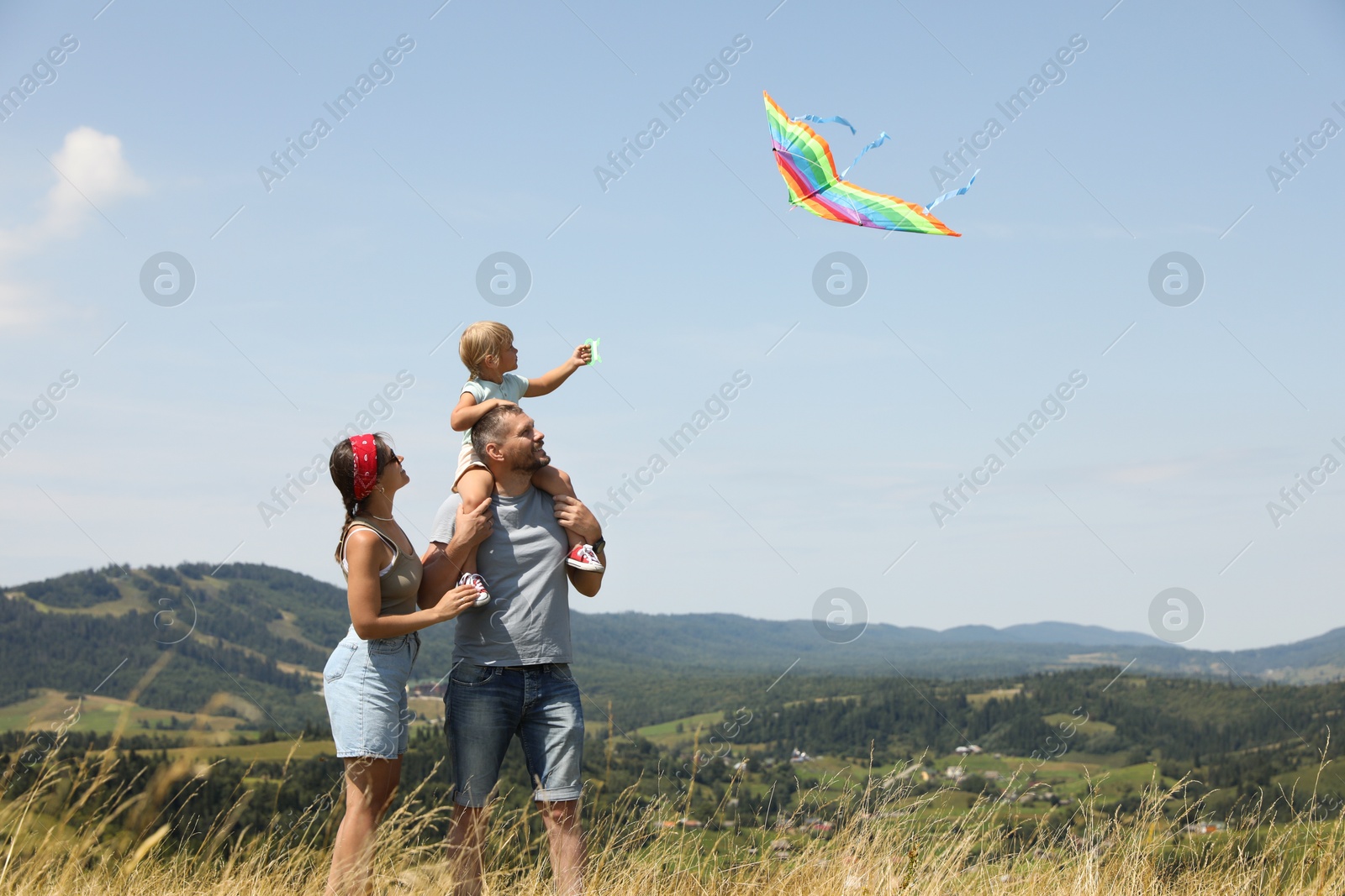 Photo of Family flying kite at field under blue sky