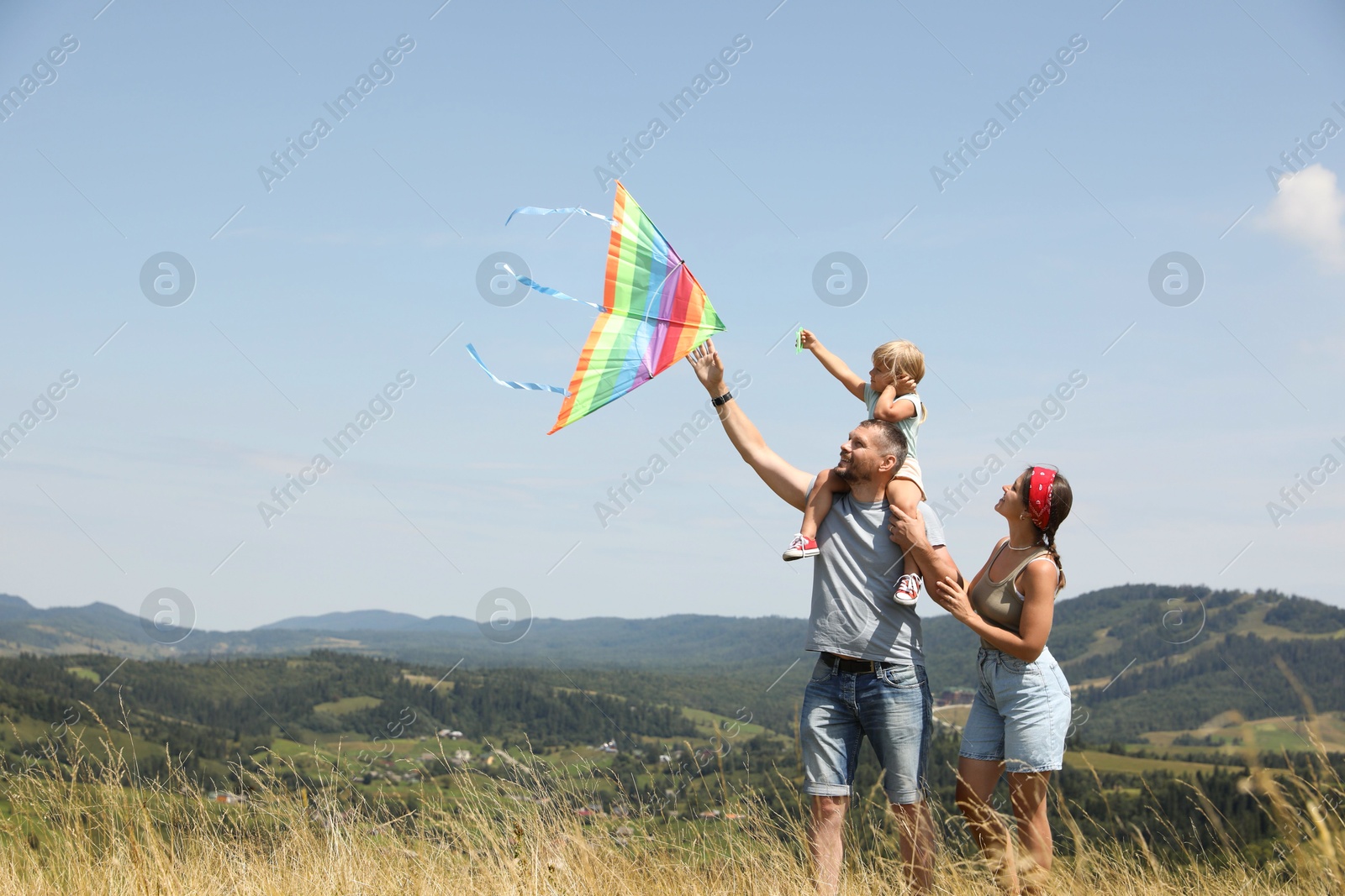 Photo of Family flying kite at field under blue sky