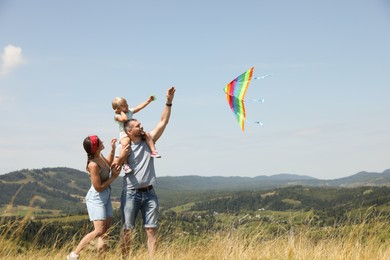 Happy family flying kite at field under blue sky