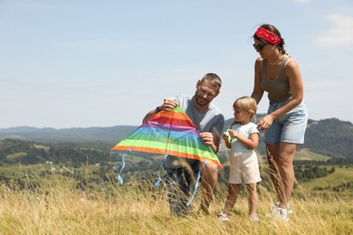 Photo of Family checking kite at field under blue sky. Space for text