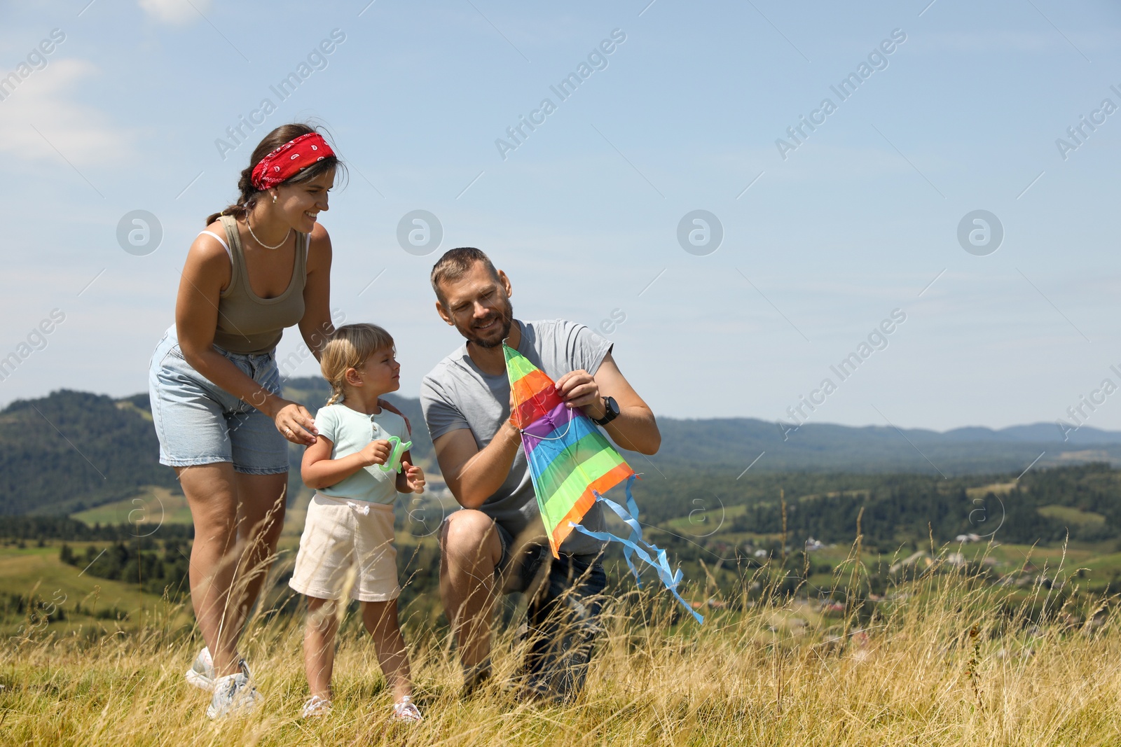 Photo of Happy family checking kite at field under blue sky. Space for text