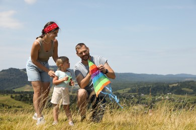 Happy family checking kite at field under blue sky. Space for text