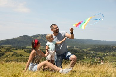 Photo of Happy family flying kite at field under blue sky