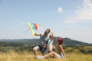 Happy family flying kite at field under blue sky