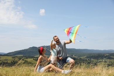 Happy family flying kite at field under blue sky