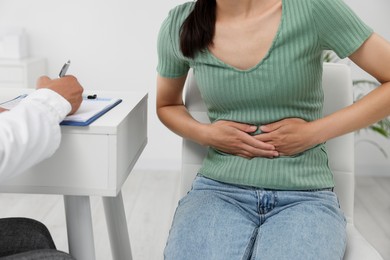 Photo of Doctor consulting patient with stomach pain at table in clinic, closeup