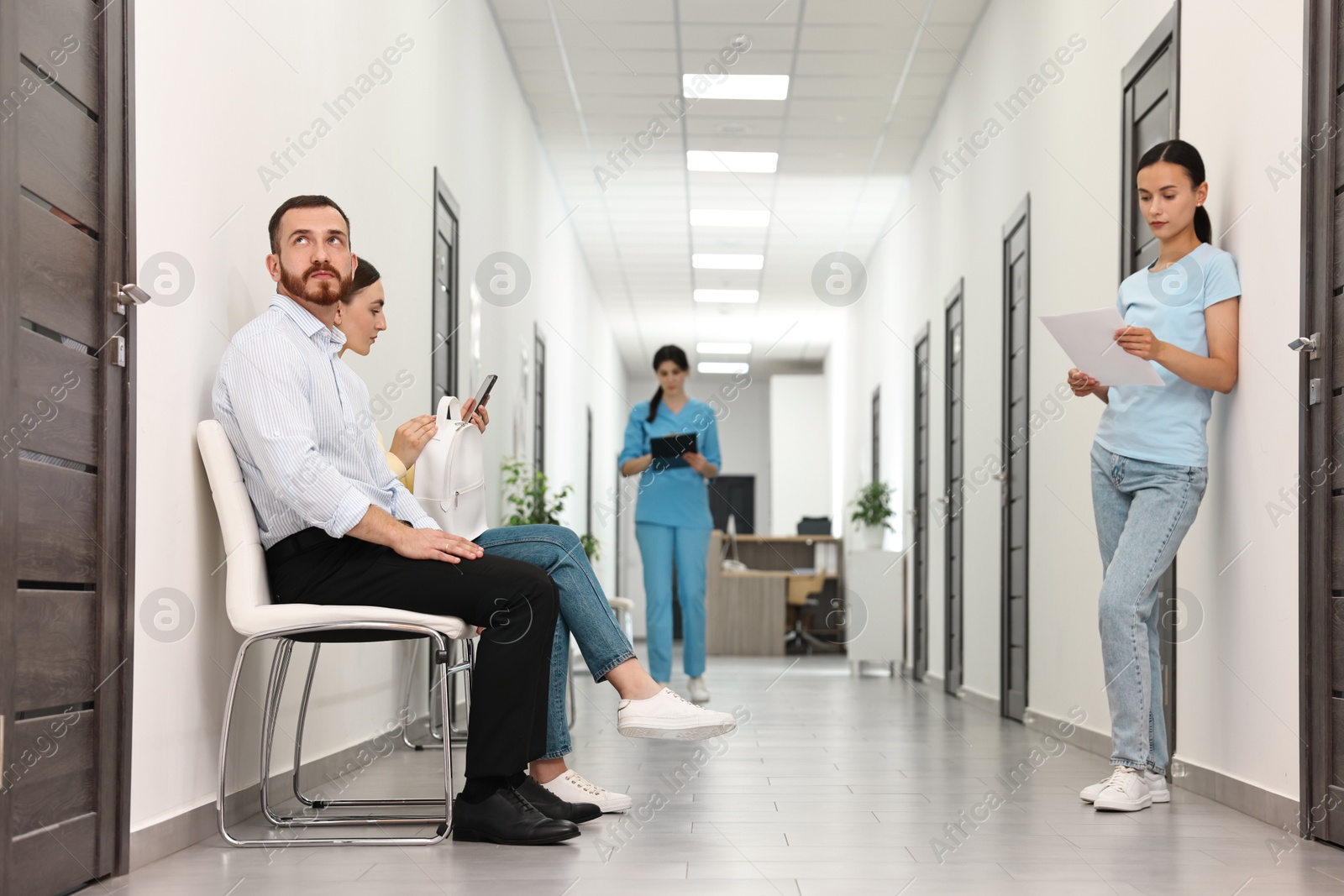 Photo of Patients waiting for appointment and doctor in hospital hallway, selective focus