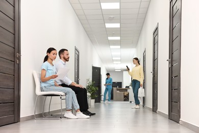 Patients waiting for appointment and doctor in hospital hallway, selective focus