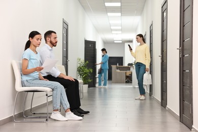 Patients waiting for appointment and doctor in hospital hallway, selective focus