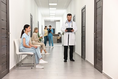 Patients waiting for appointment and doctors in hospital hallway, selective focus