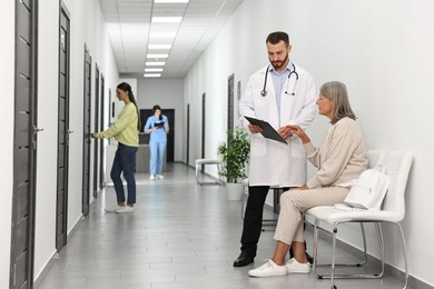 Patients waiting for appointment and doctors in hospital hallway, selective focus