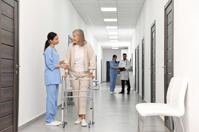 Nurse with senior woman in hospital hallway