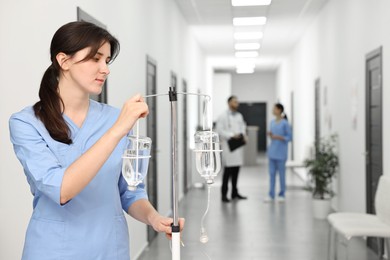 Nurse with IV drip in hospital hallway, selective focus