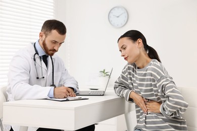 Photo of Doctor consulting patient with stomach pain at table in hospital