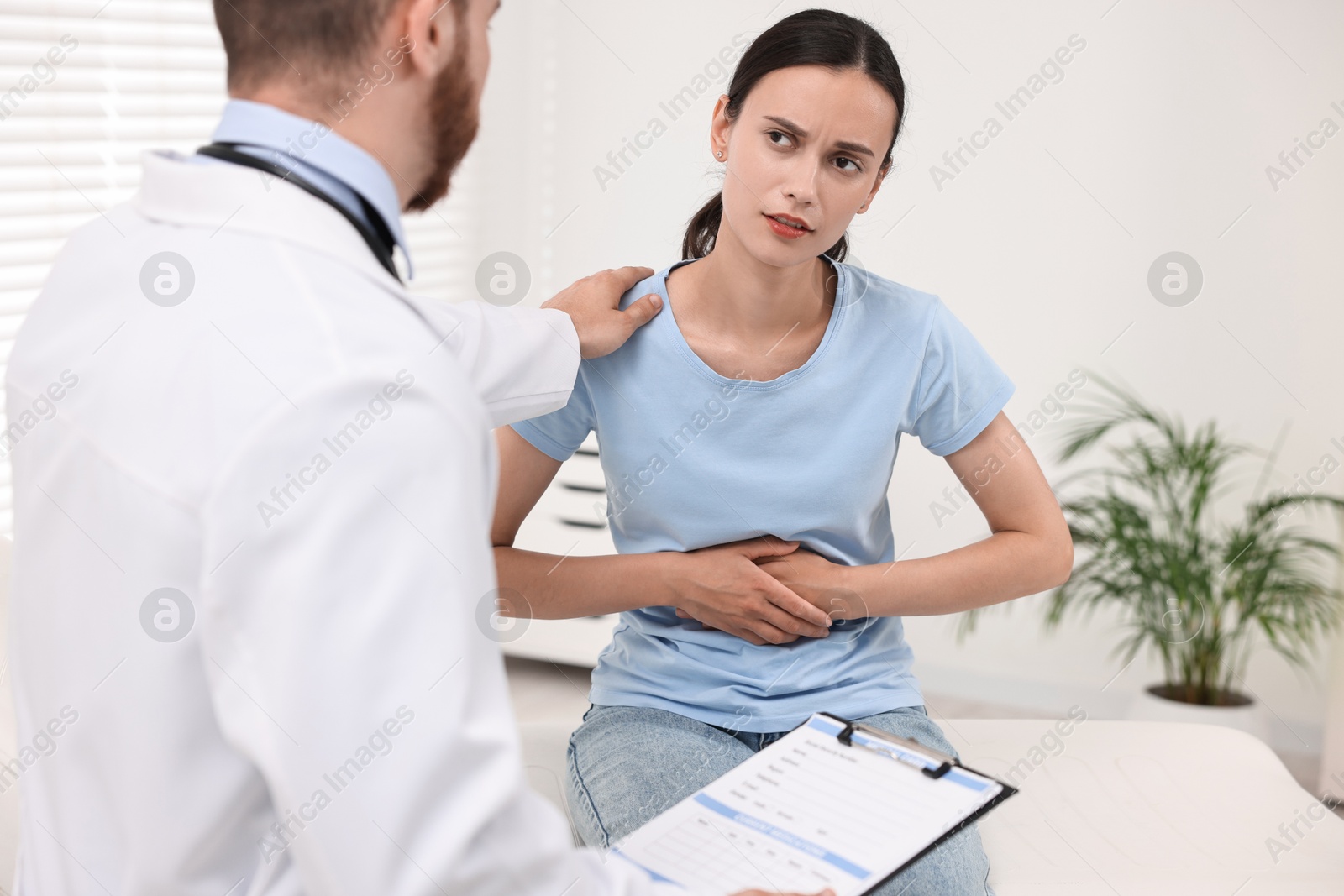 Photo of Doctor consulting patient with stomach pain in clinic