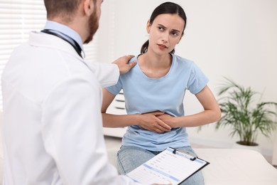 Doctor consulting patient with stomach pain in clinic