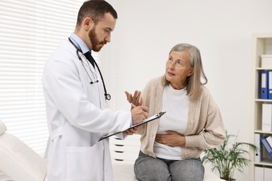 Doctor consulting senior patient with stomach pain in clinic