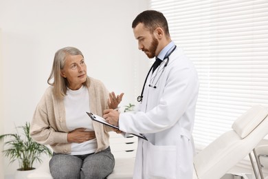 Doctor consulting senior patient with stomach pain in clinic