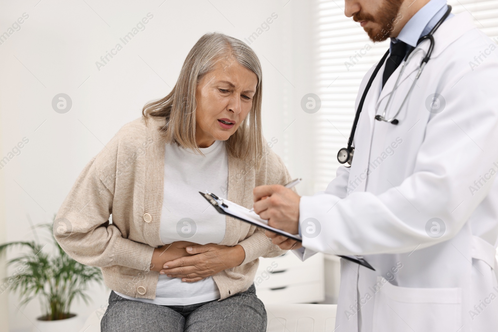 Photo of Doctor consulting senior patient with stomach pain in clinic, closeup