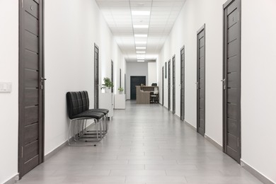 Empty hospital corridor with chairs and doors