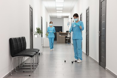 Nurses working with medical equipment in hospital hallway