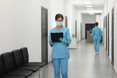 Nurse working with clipboard in hospital hallway