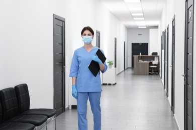 Photo of Nurse in uniform with clipboard in hospital hallway