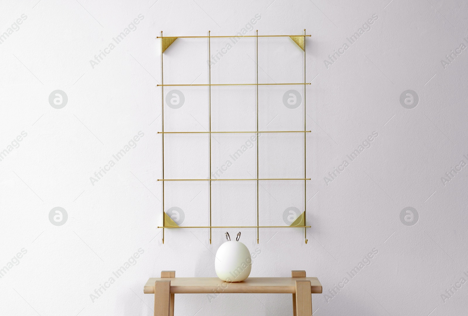 Photo of Golden metal mood board and night light on wooden ladder near white wall