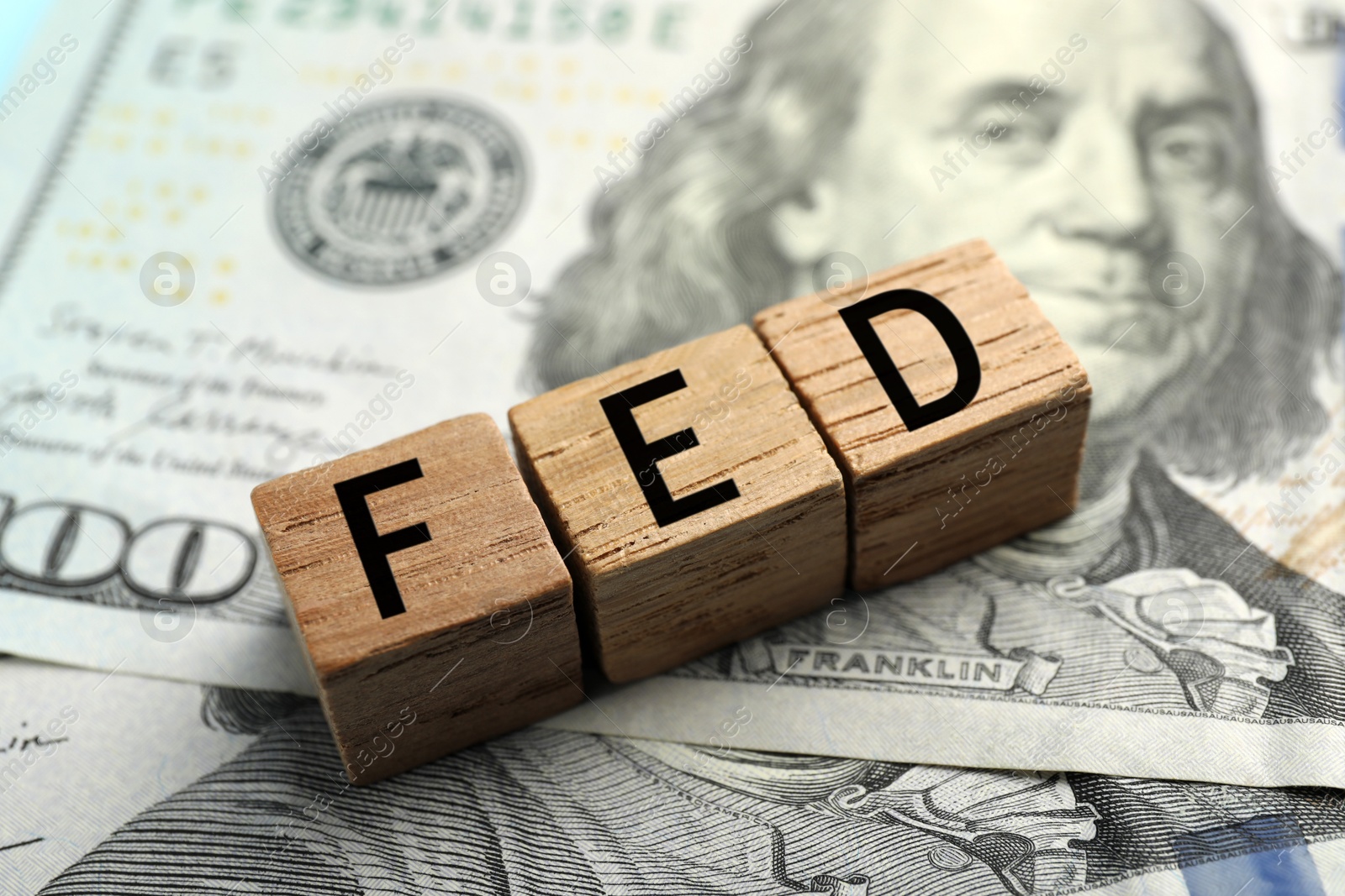 Photo of Wooden cubes with letters Fed (Federal Reserve System) on dollar banknotes, closeup