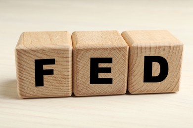 Photo of Wooden cubes with letters Fed (Federal Reserve System) on table, closeup