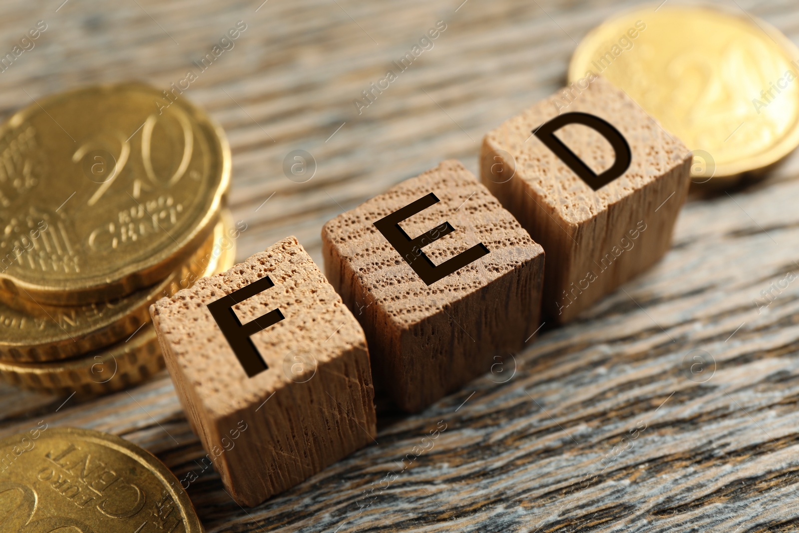 Photo of Cubes with letters Fed (Federal Reserve System) and coins on wooden table, closeup