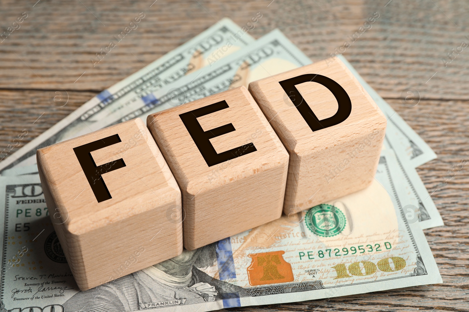 Photo of Wooden cubes with letters Fed (Federal Reserve System) and dollar banknotes on table