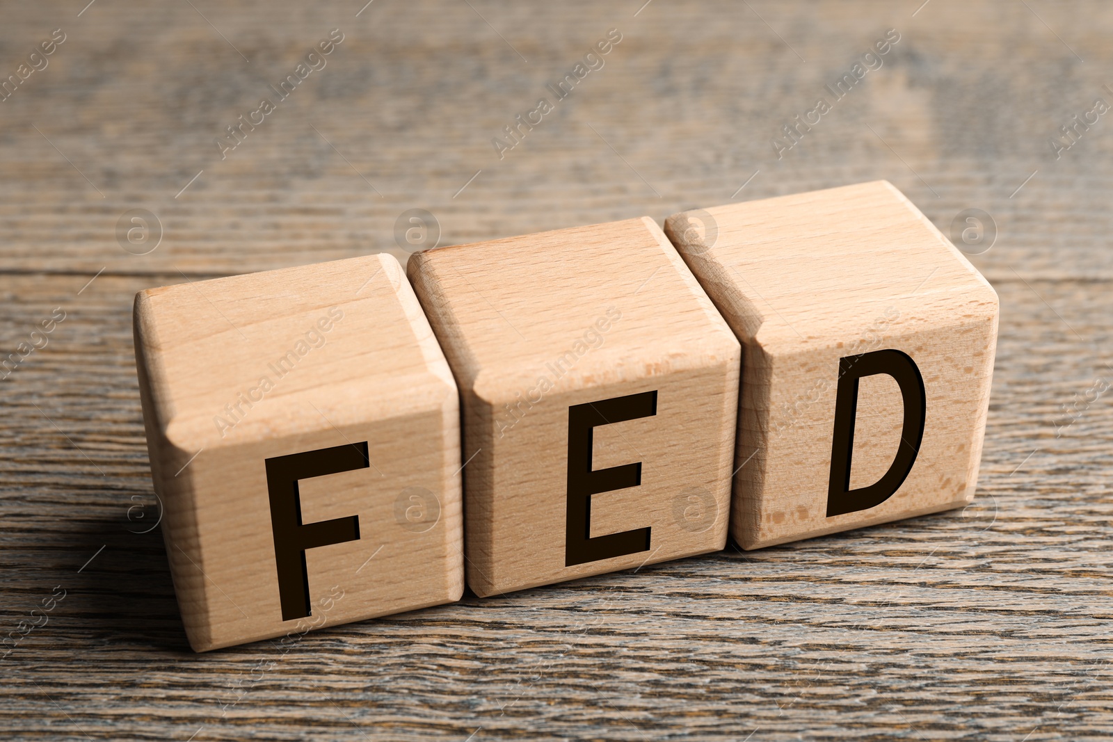 Photo of Cubes with letters Fed (Federal Reserve System) on wooden table, closeup