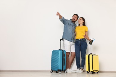 Photo of Happy couple with suitcases indoors, space for text