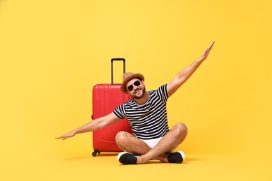 Happy man in sunglasses and suitcase on orange background