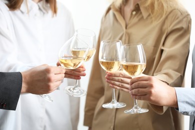 People clinking glasses of wine indoors, closeup