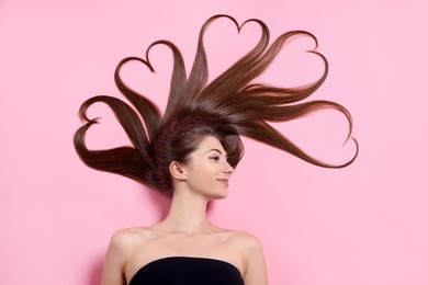 Beautiful young woman with hair in shape of hearts on pink background, top view