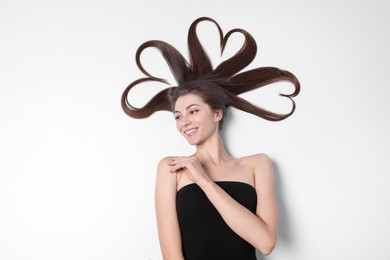 Beautiful young woman with hair in shape of hearts on white background, top view